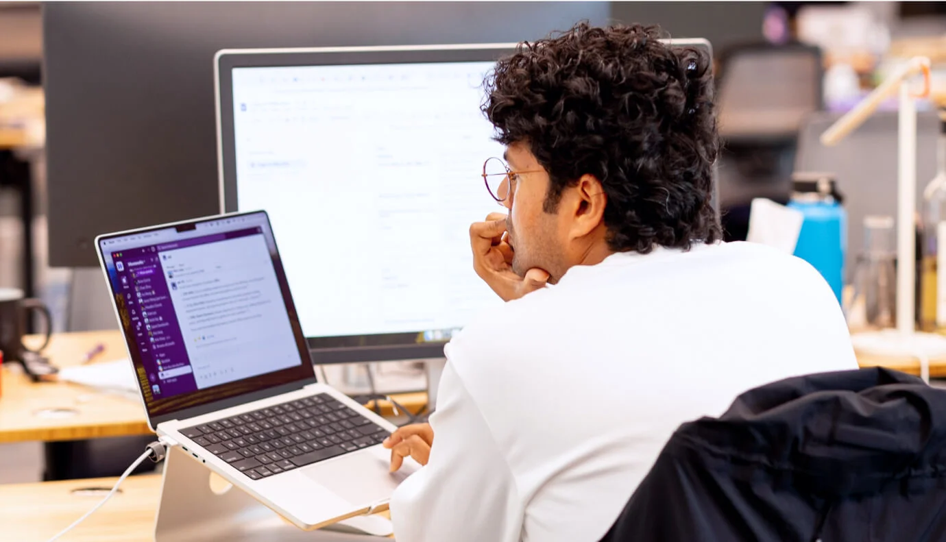 employee-at-desktop-looking-at-slack-on-laptop